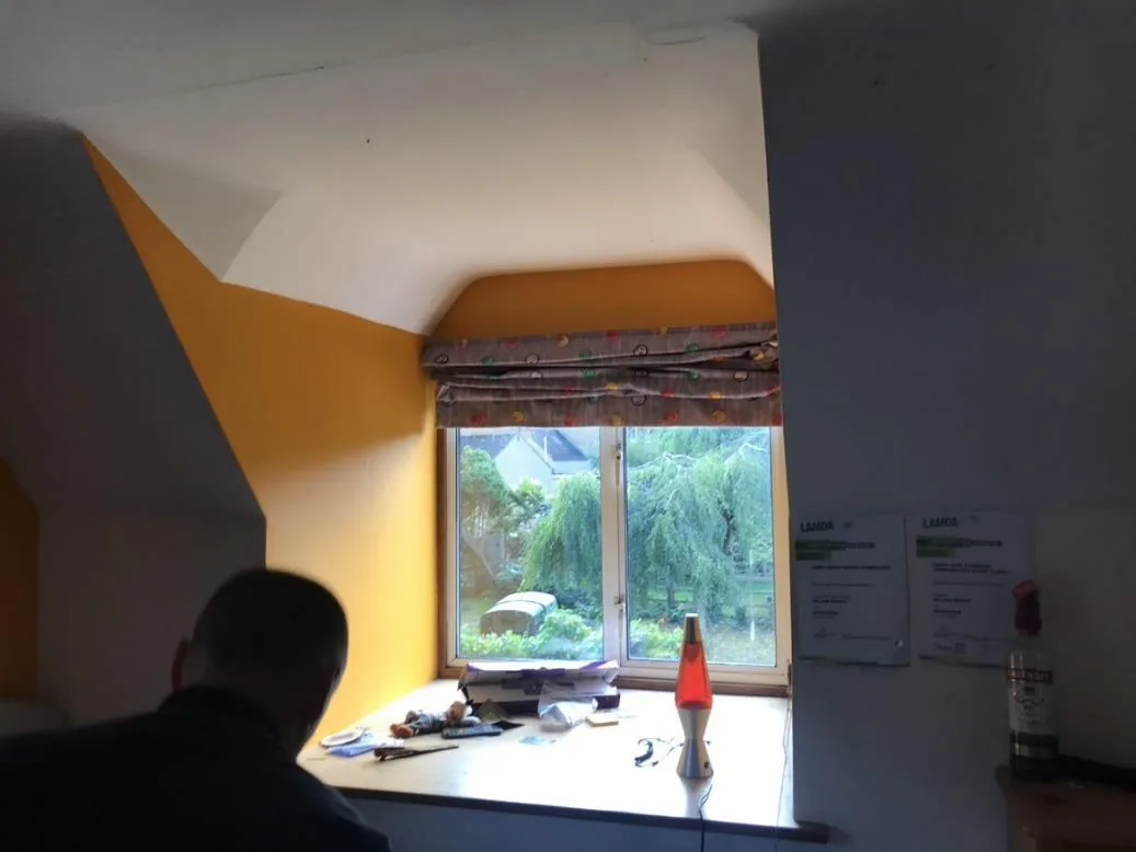 A bedroom with sloping ceilings following the rafters, before insulation